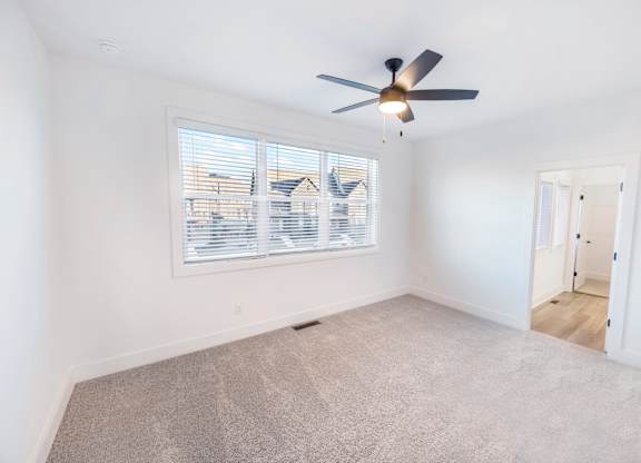 A room with a ceiling fan and a window with blinds.