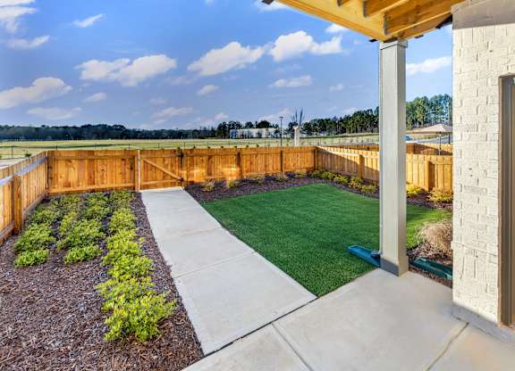A backyard with a wooden fence and a green lawn.