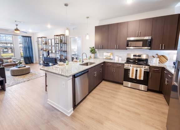 A modern kitchen with wooden floors and stainless steel appliances.