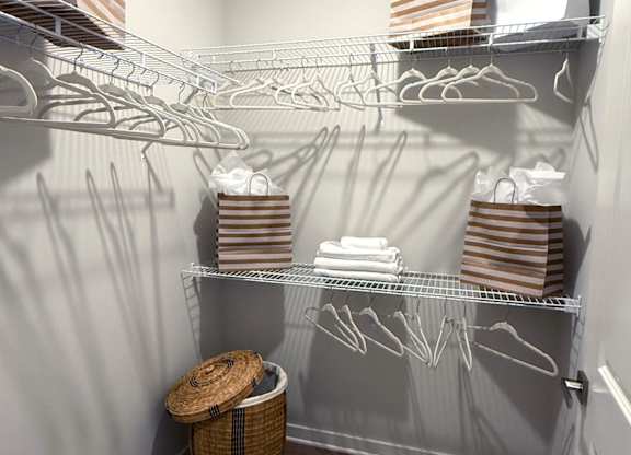 A laundry room with a basket and clothes on the shelves.