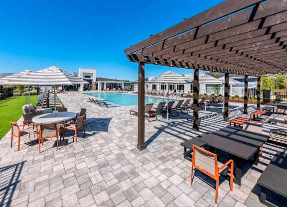 A patio with a table and chairs overlooking a pool.