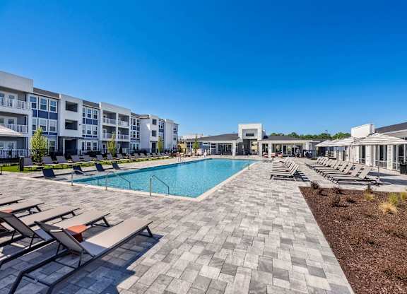A sunny day at a poolside with apartment buildings in the background.