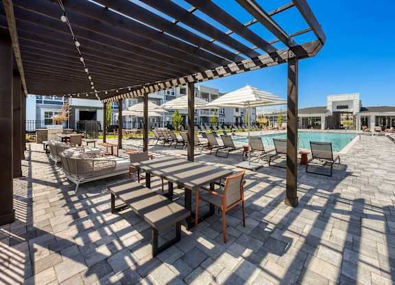 A patio with a table and chairs under a wooden pergola.
