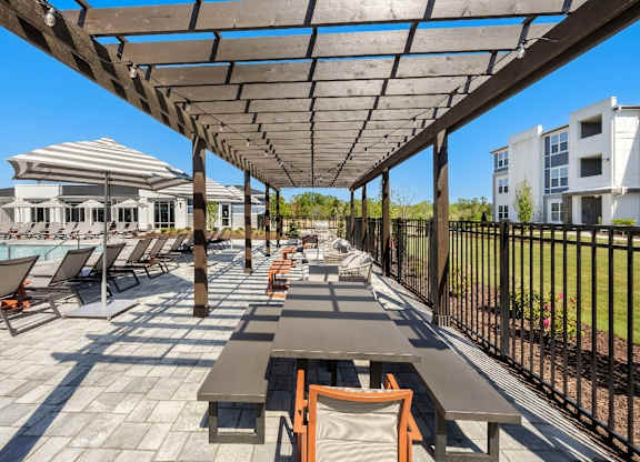 A sunny day at the poolside with loungers and tables.