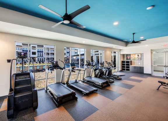 A gym with treadmills, elliptical machines, and a fan.
