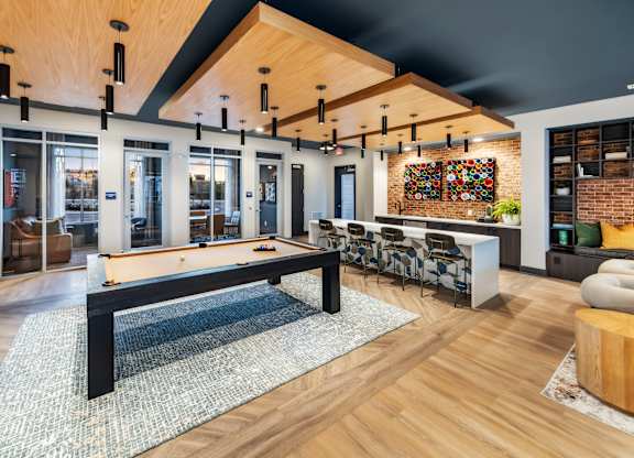 A modern living room with a pool table and a brick wall.