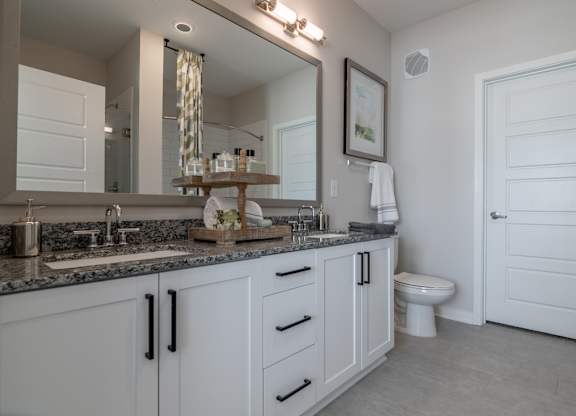 a bathroom with white cabinets and a large mirror and a toilet