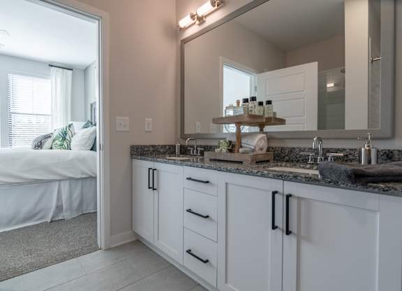 a bathroom with a sink and a mirror and a bedroom with a bed
