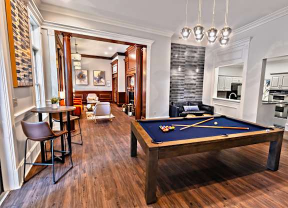 A pool table is in the middle of a room with a wood floor.