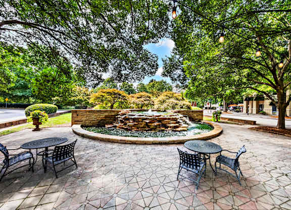 A patio with a table and chairs overlooking a fountain.