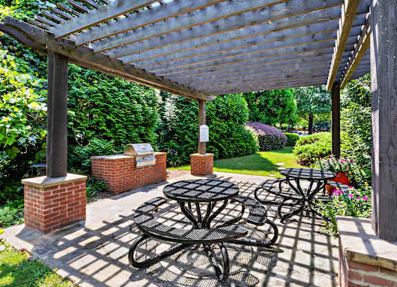 A patio with a table and chairs under a wooden pergola.