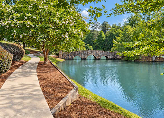 A stone bridge over a body of water with a concrete walkway on the left.