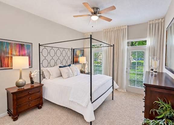 A bedroom with a four poster bed and a ceiling fan.
