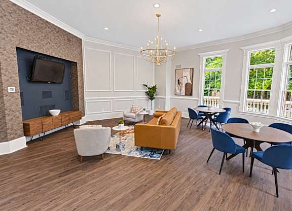A living room with a television, sofas, chairs, and a chandelier.