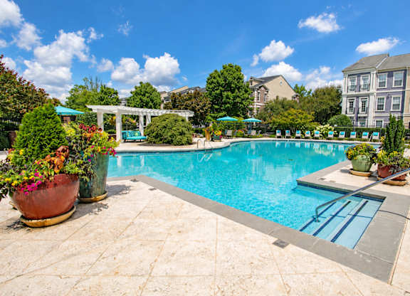 A pool surrounded by a patio and a garden.