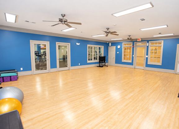 A spacious room with wooden floors and exercise equipment.