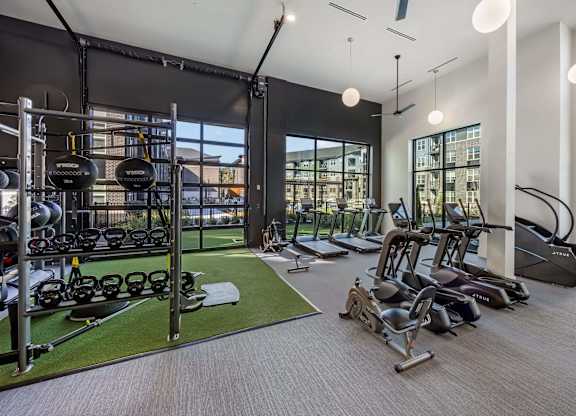 A gym with a variety of equipment including treadmills, weights, and exercise machines.