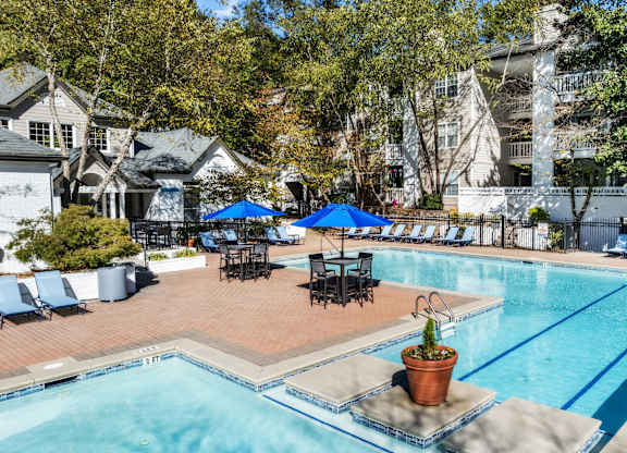 A pool area with a blue umbrella and chairs at The Point at Perimeter, Georgia, 30338