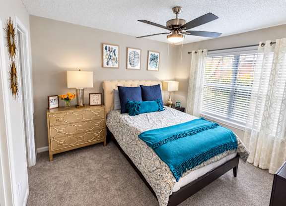 A bedroom with a bed, dresser, and ceiling fan.