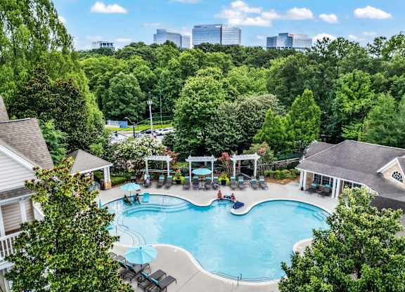 A swimming pool surrounded by trees and houses.