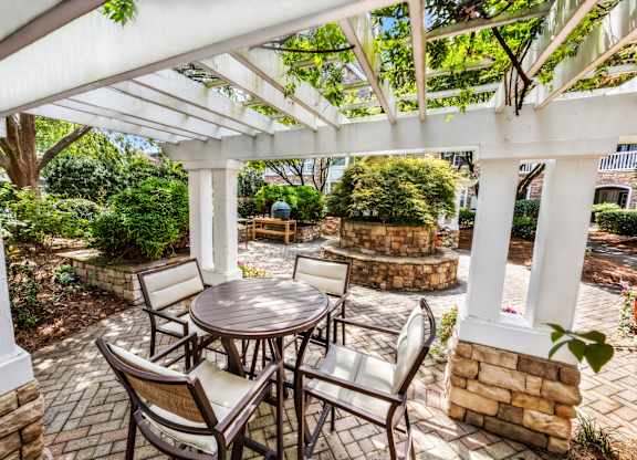 A patio with a table and chairs under a white pergola.
