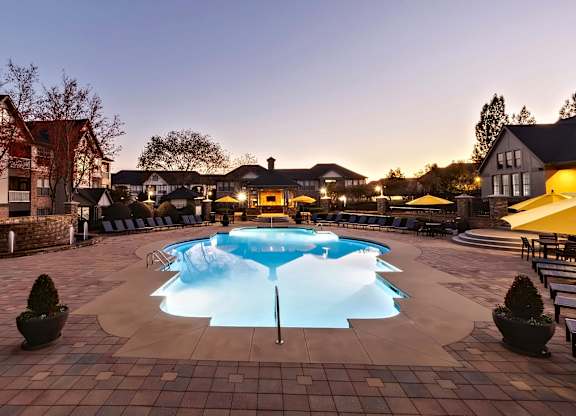 Swimming pool at dusk with lounge seating.