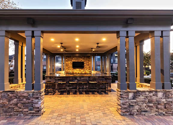 A stone and tile patio with a fireplace and seating area.