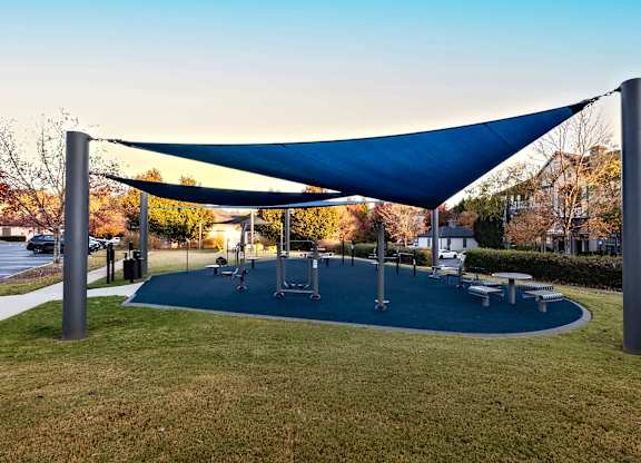 A playground with a blue canopy and a green mat.