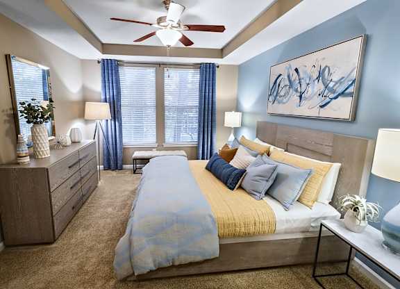 A bedroom with a bed, nightstands, and a ceiling fan.