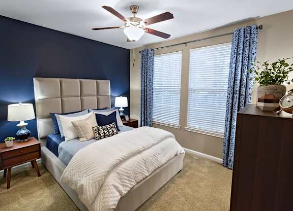 A bedroom with a bed, nightstand, and window.