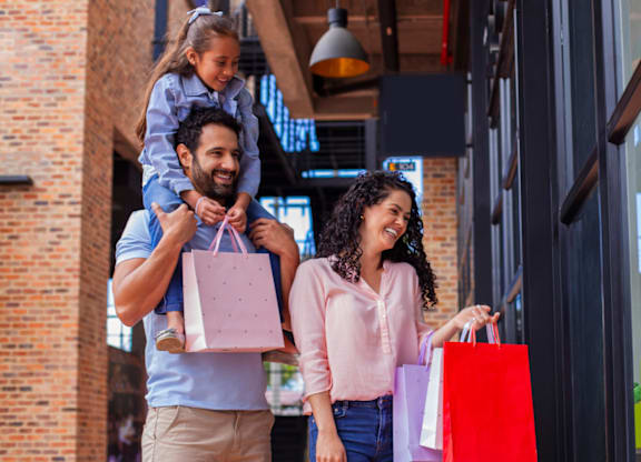 A family of three, a man, a woman and a child, are shopping together.