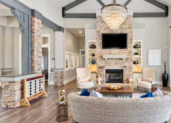 A living room with a grey couch and a stone fireplace.