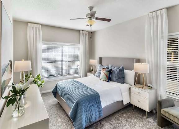 A bedroom with a bed, nightstands, and a ceiling fan.