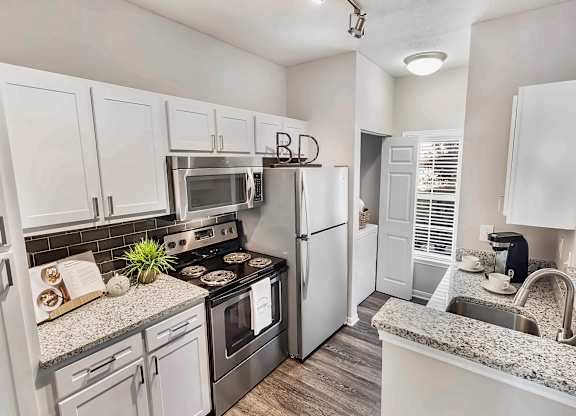A kitchen with white cabinets and a granite countertop.