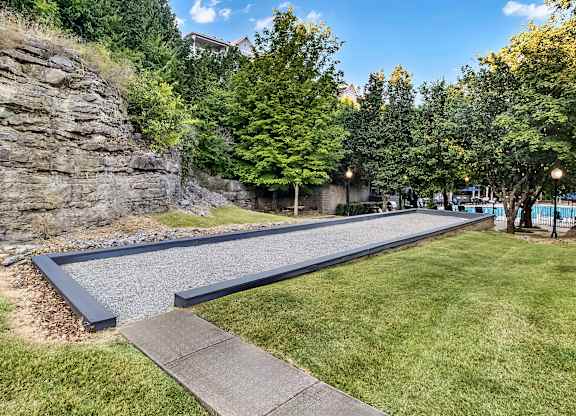 A walkway with a stone wall on one side and a grassy area on the other.