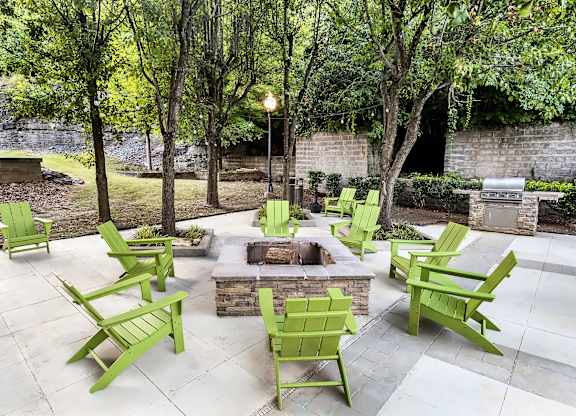 A patio with green chairs and a fire pit.