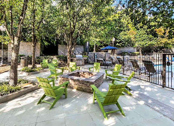 A patio with a fire pit and chairs.