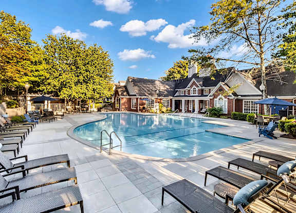 A large outdoor swimming pool surrounded by sun loungers and trees.