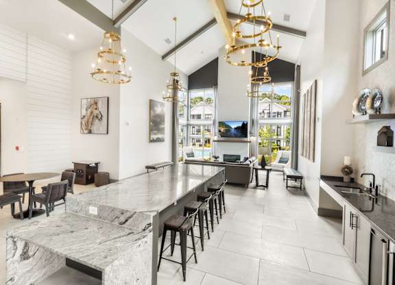 A modern kitchen with a marble island and black chairs.