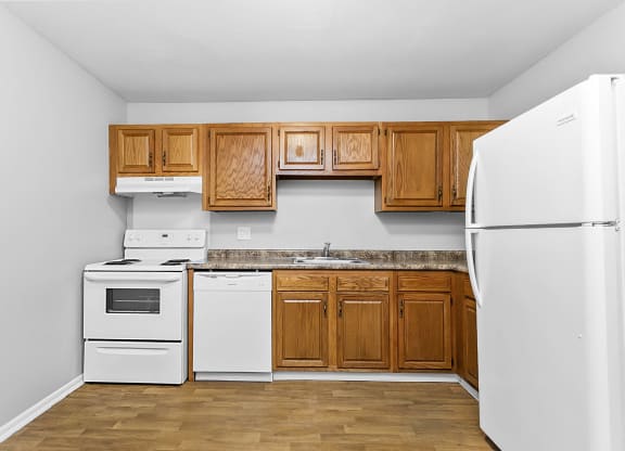 a kitchen with white appliances and wooden cabinets at Eagle Pointe New London, CT, 06320