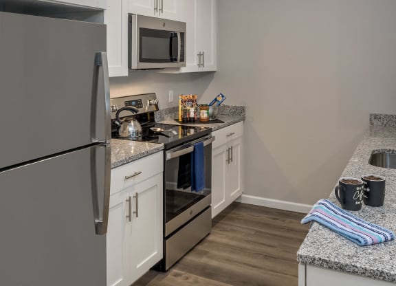 a kitchen with stainless steel appliances and white cabinets at Eden & Main 55+ Apartments, Southington, CT 06489