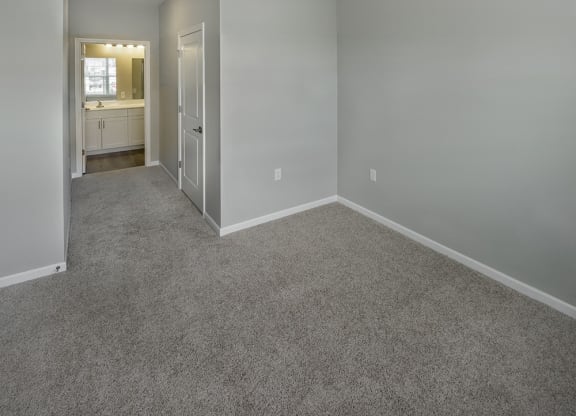 an empty room with a carpeted floor and a door to a bathroom at Eden & Main 55+ Apartments, Southington , Connecticut