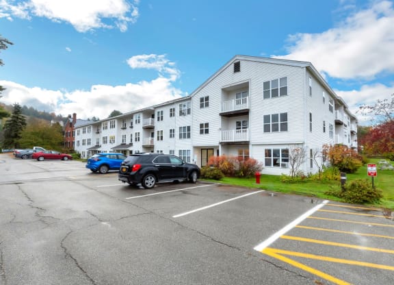 an apartment building with a parking lot and cars in front of it