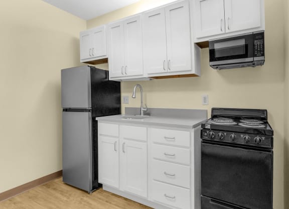 a kitchen with white cabinets and black appliances and a refrigerator