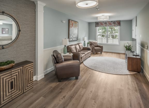 a living room with leather furniture and a rug at Eden & Main 55+ Apartments, Southington