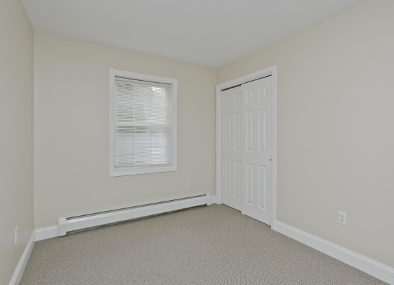 a bedroom with white walls and a white door and a window