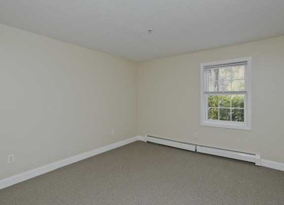 a bedroom with white walls and a window