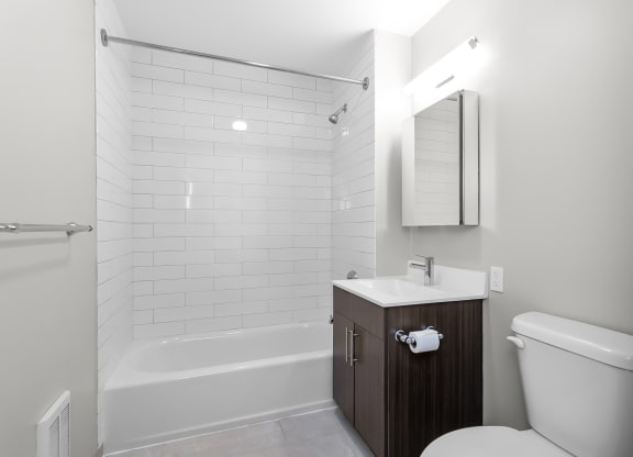 a bathroom with a toilet sink and tub and a mirror  at 1188 Lofts, Bridgeport, Connecticut