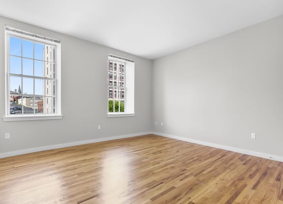 an empty room with wood floors and two windows at 1188 Lofts, Bridgeport