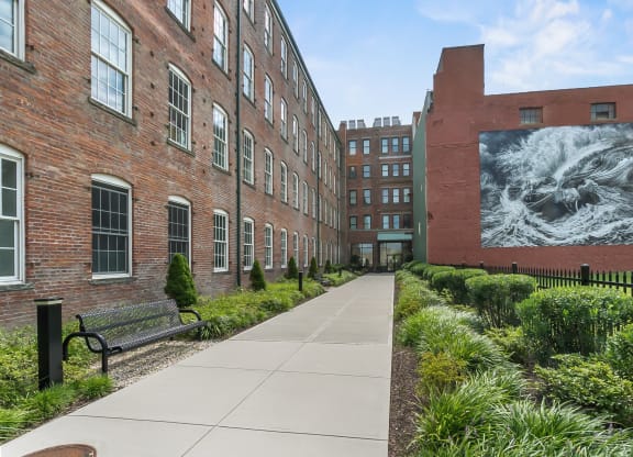 a sidewalk in front of a building with a large mural on the side at 1188 Lofts, Bridgeport, CT